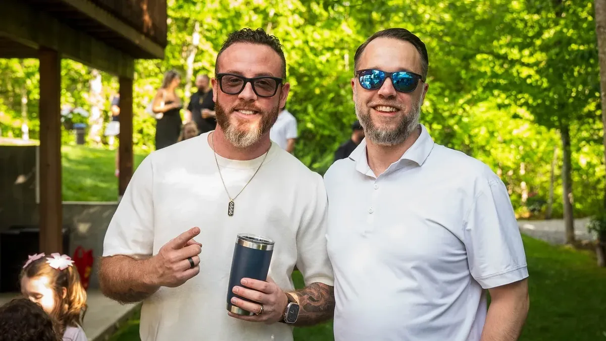 Two guests laughing together at an outdoor backyard event