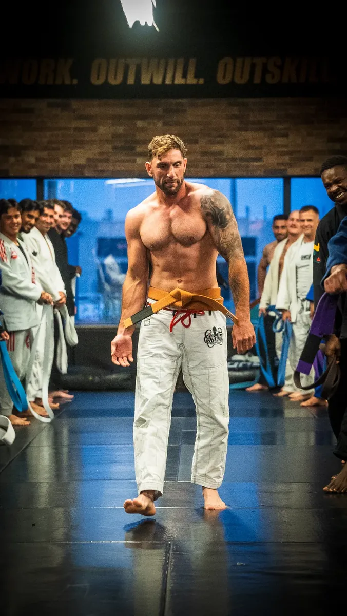 Newly promoted grappler walking the line of teammates after a belt ceremony