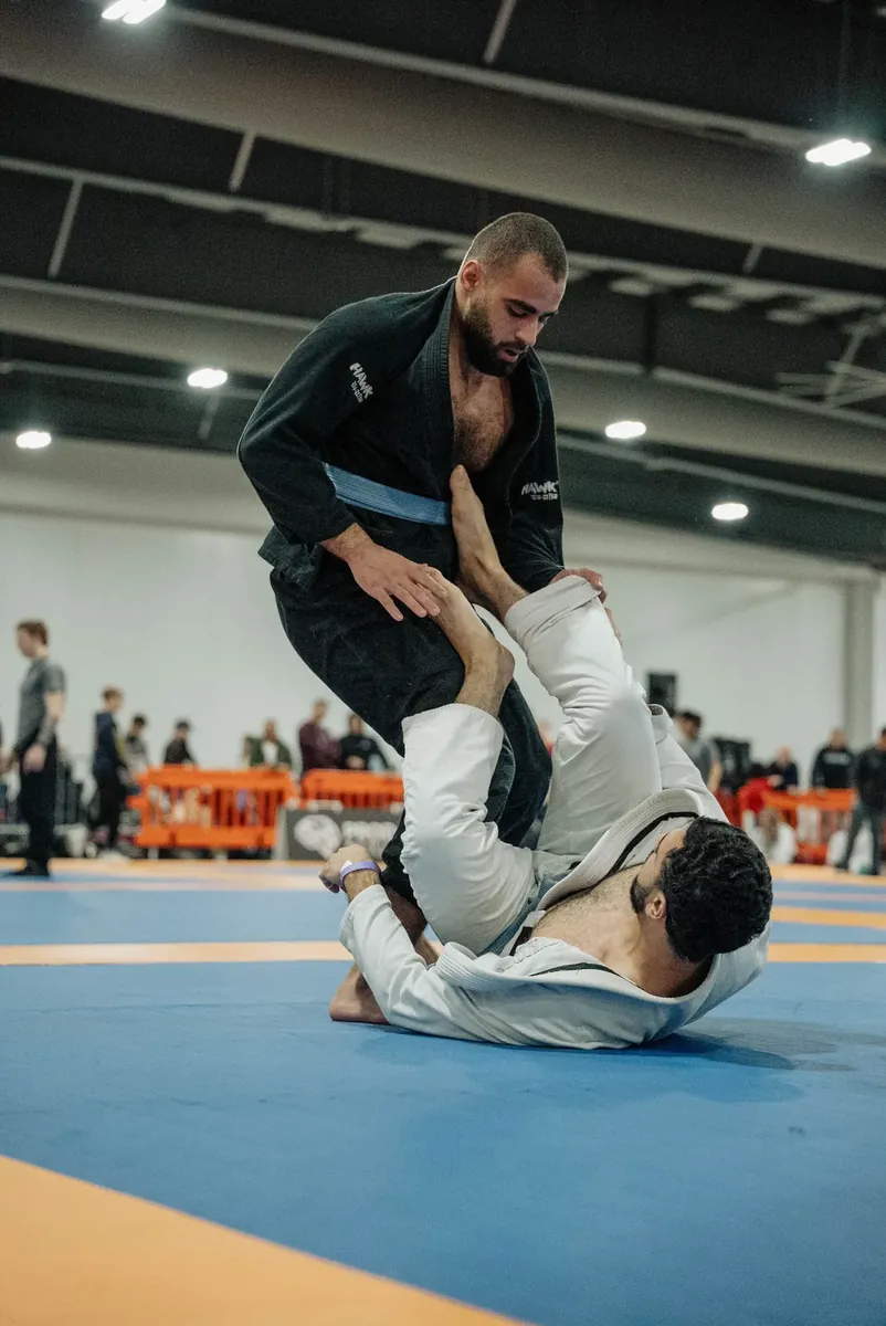 Competitor passing guard against a downed opponent on the tournament mats