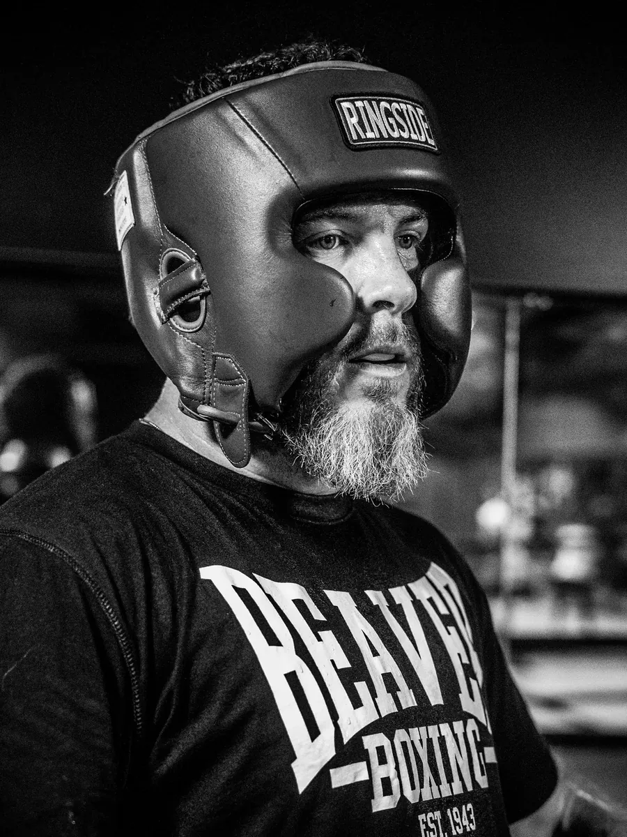 Bearded boxer in Ringside headgear and a Beaver Boxing tee, catching his breath