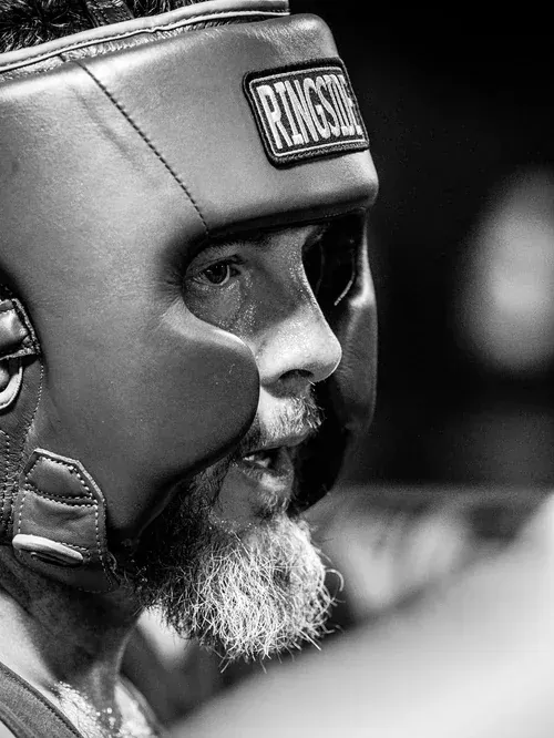Profile of a bearded boxer in Ringside headgear between rounds
