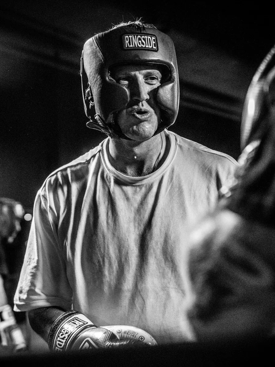 Boxer in headgear between rounds, gloves up and soaked through