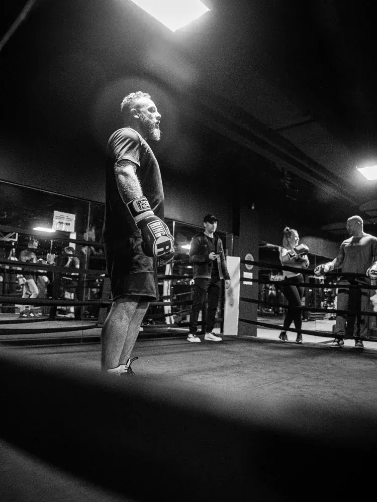 Boxer standing alone in the ring under an overhead light before a round