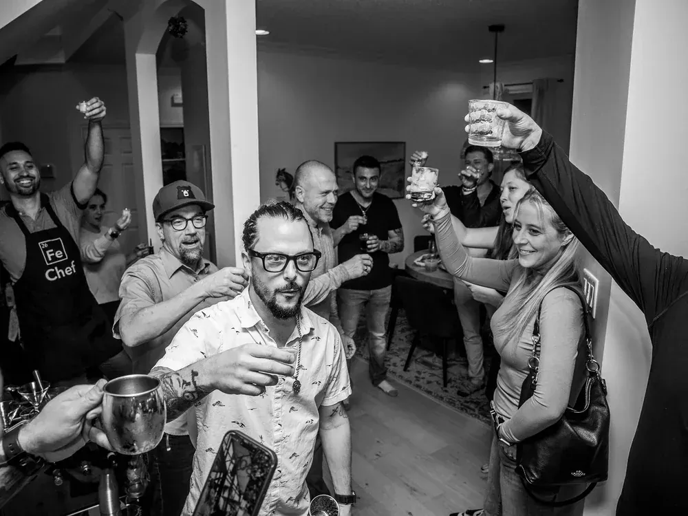 A crowded room raising glasses for a toast at a house party