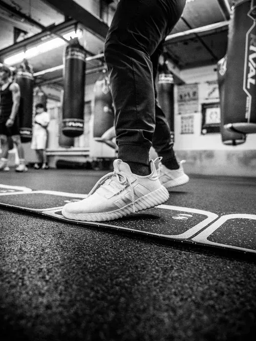 Low, tight frame of a boxer's feet on the footwork line at the gym