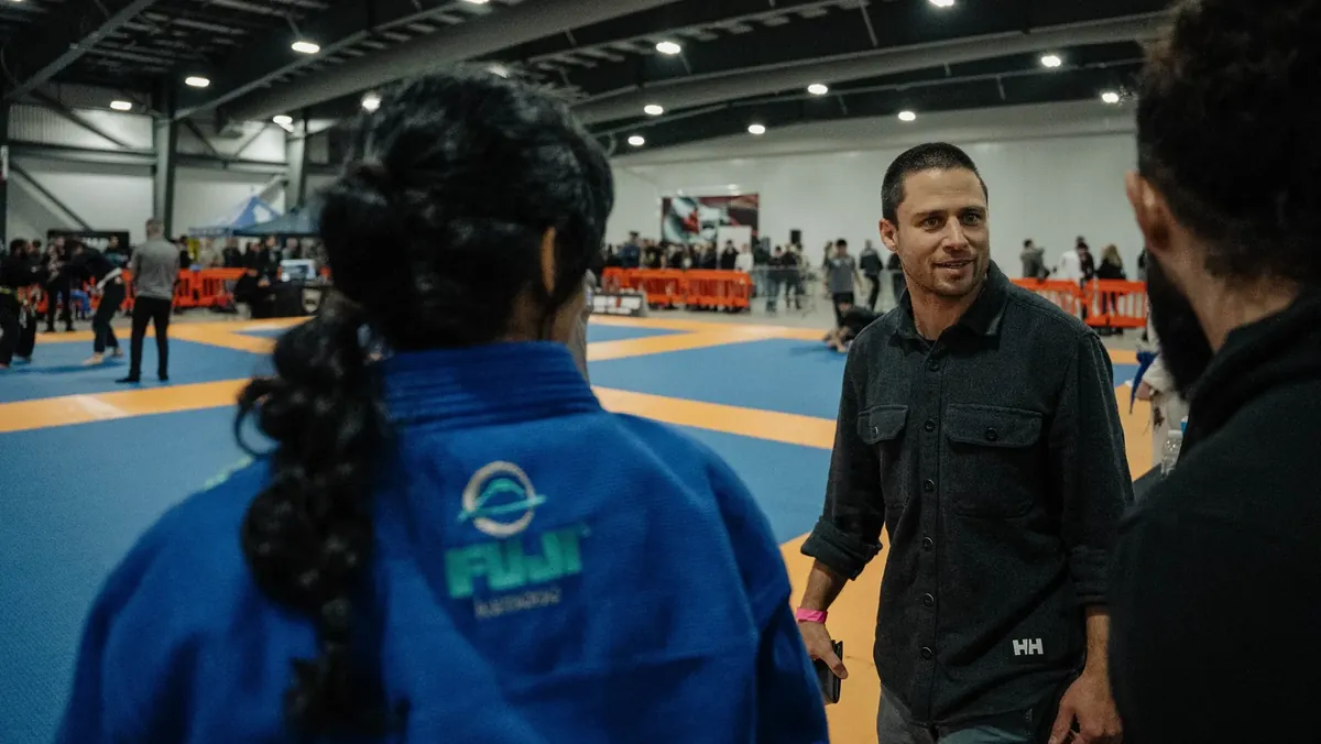 Coach talking with two competitors at the edge of the tournament mats