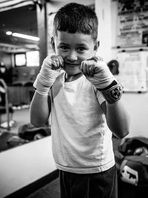 Young boxer in wrapped hands smiling with his guard up at the gym